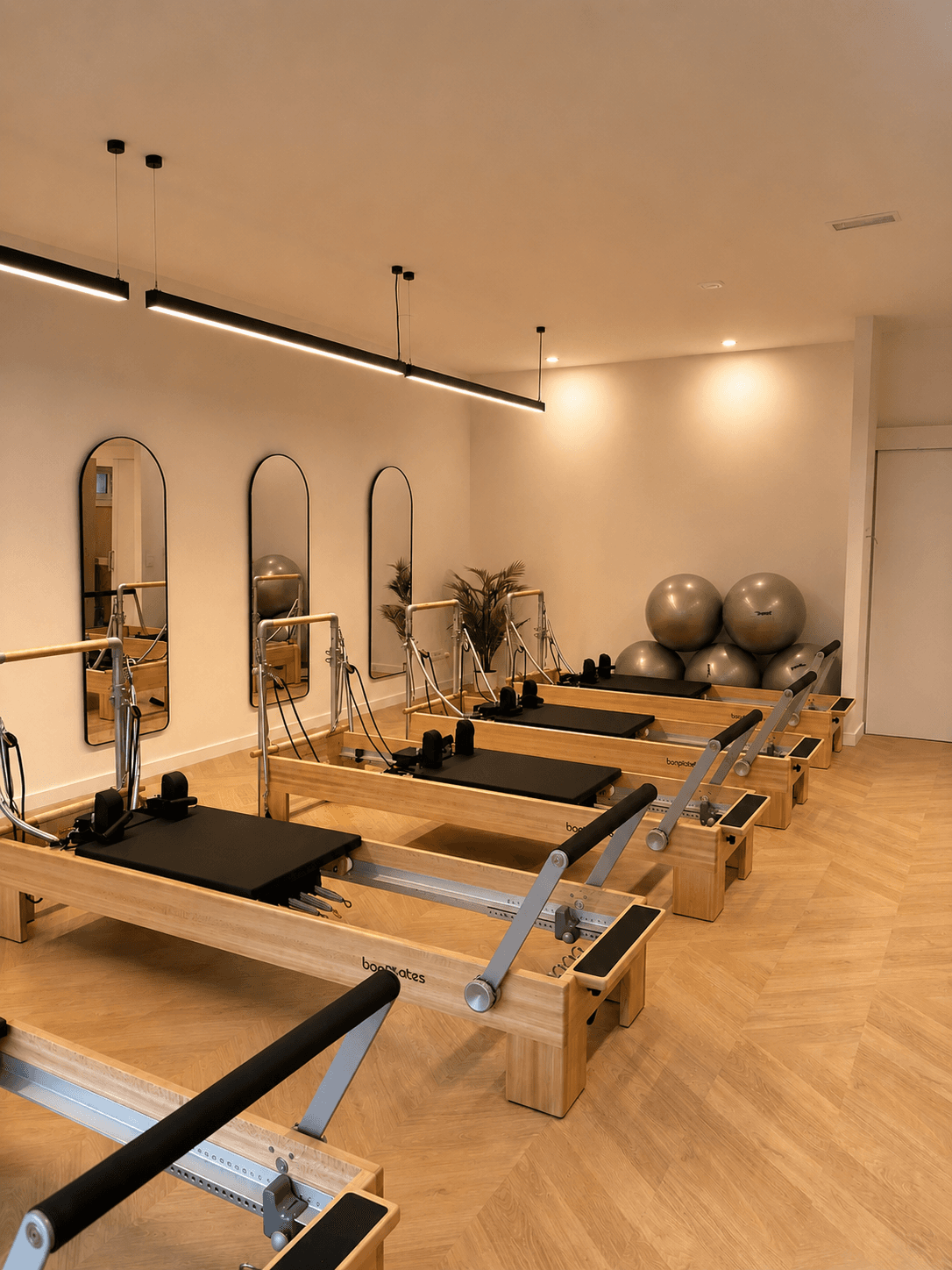 Sala de Aura Pilates Studio con máquinas Reformer, espejos y luz cálida, Vallcarca Barcelona